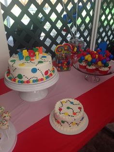 a table topped with two cakes covered in frosting next to other desserts and candies