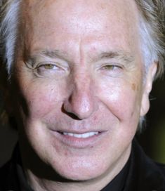 a close up of a person wearing a black shirt and tie smiling at the camera