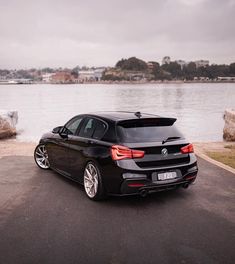 a black car parked on the side of a road next to water