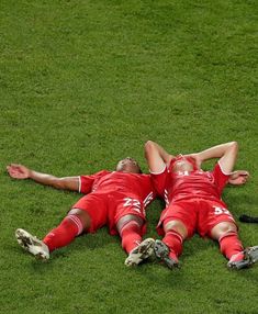 two soccer players laying on the ground with their arms around each other and one holding his head