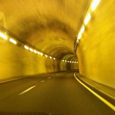 a car driving through a tunnel with light at the end and no cars on it