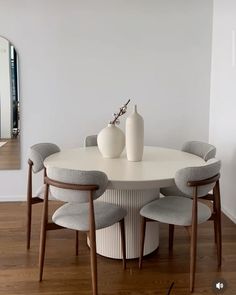 a white table with four chairs and two vases sitting on it's side