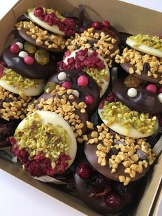 a box filled with chocolate covered donuts topped with nuts and sprinkles