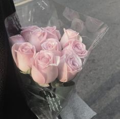 a bouquet of pink roses sitting on the side of a road next to a person