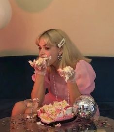 a woman sitting at a table with a cake in front of her and confetti all over her face