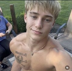 a shirtless young man sitting on a wooden deck