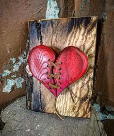 a wooden box with a red heart and laces on the inside, sitting on top of a piece of wood