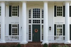 a white house with black shutters and a wreath on the front door is shown