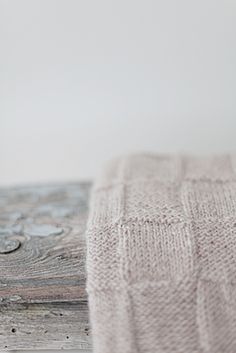 a close up of a wooden surface with water droplets on it and a white wall in the background