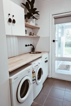 a white washer sitting next to a window in a room with tile flooring