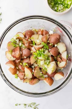 a glass bowl filled with potatoes and celery on top of a white table