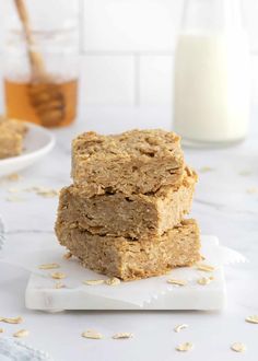 three oatmeal bars stacked on top of each other next to a glass of milk