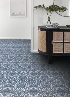 a blue and white patterned floor in a room with a plant on the sideboard