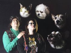 two people standing next to each other with dogs and cats on their heads in front of them