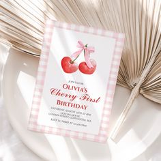 a pink gingham cherries birthday party card on top of a white plate