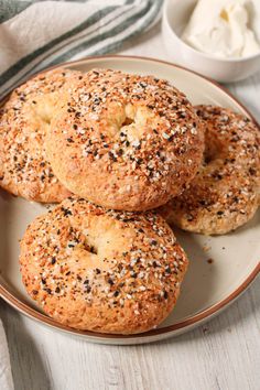 three bagels on a plate with butter and poppy seed sprinkles next to it