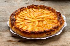 a pie on a wooden table topped with sliced peaches