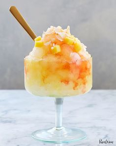 an ice cream sundae with pineapple and coconut toppings on a marble table