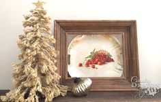 a small christmas tree sitting on top of a wooden shelf next to a plate and silver ornament