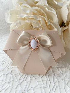 a white flower sitting on top of a table next to a pink box with a bow