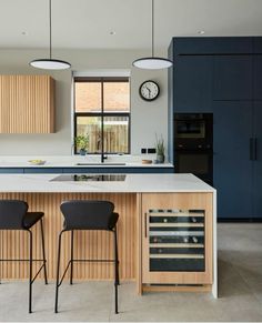 a kitchen with two bar stools next to an oven and counter top that has a clock on the wall