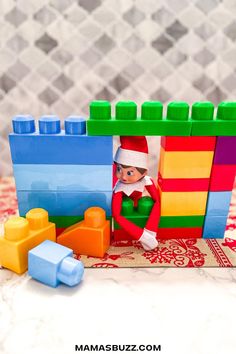 the elf is playing with his toys on the table in front of the building blocks