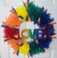 a wreath with the word love painted on it and rainbow ruffles in front