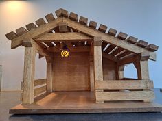 a small wooden structure with a lantern hanging from it's roof, in front of a white wall