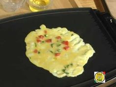 an omelet with tomatoes and spinach on it sitting on a black plate