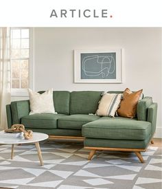 a living room with a green couch and coffee table in front of a painting on the wall