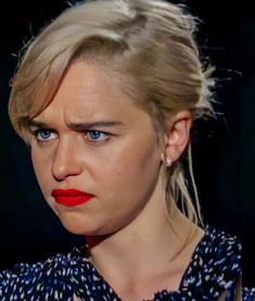 a woman with blonde hair and blue eyes wearing a red lipstick in front of a black background