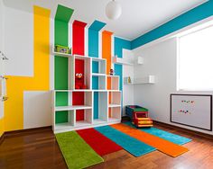 a brightly colored room with bookshelves and rugs on the hardwood flooring