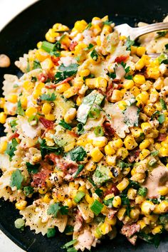 a black plate topped with corn salad next to a fork