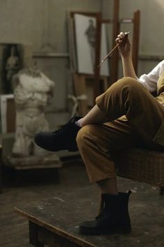 a woman sitting on top of a wooden table holding a stick in her hand and looking at the camera