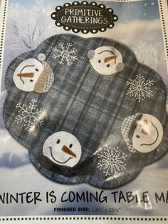 a package of winter is coming table mats with snowman faces on the front and back