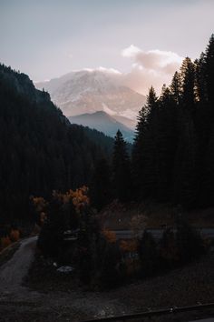 the mountains are covered in snow and trees as the sun is setting on top of them