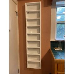 an empty white book shelf in the corner of a kitchen