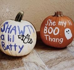 two painted pumpkins sitting on top of a tile floor next to each other with words written on them