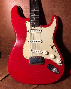 a red electric guitar sitting on top of a brown couch