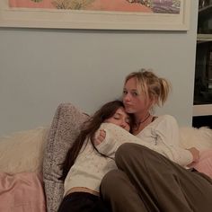 two women sitting on a bed hugging each other