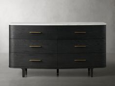 a black and white dresser with gold pulls on it's drawers, against a gray wall