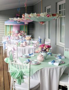 a table set up for a tea party with pink and blue flowers on the tables