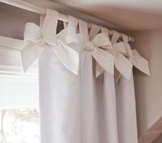 a white curtain with bows hanging from it's side in front of a window