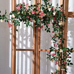 an arch with pink and white flowers hanging from it's sides in front of a wall