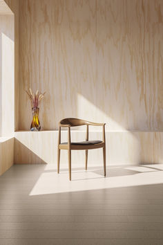 a wooden chair and vase with flowers in it on a shelf next to a window