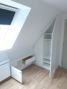 an attic bedroom with white walls and wooden floors, built - in shelving unit