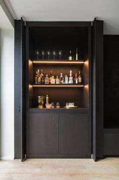 an open cabinet with bottles and glasses on it