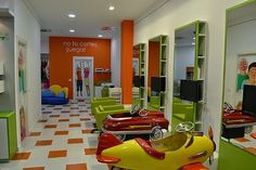 the interior of a hair salon with colorful chairs and mirrors on the wall, two children's toy cars in front of them