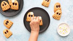 someone is decorating cookies with fake eyes and flowers on the plate next to them