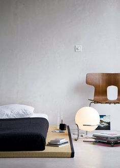 a bed sitting next to a wooden chair on top of a white floor